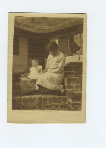 On brick steps in front of a thatched cottage